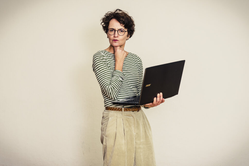 Blogbeitrag schreiben: Frau mit Laptop mit grübelndem Blick