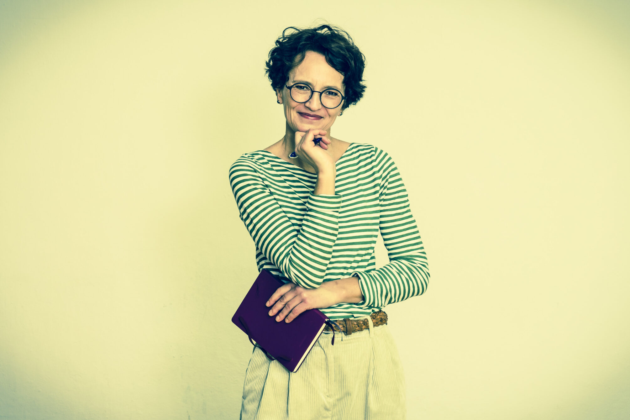 Frau schaut lächelnd in die Kamera, hat Kalender in der Hand