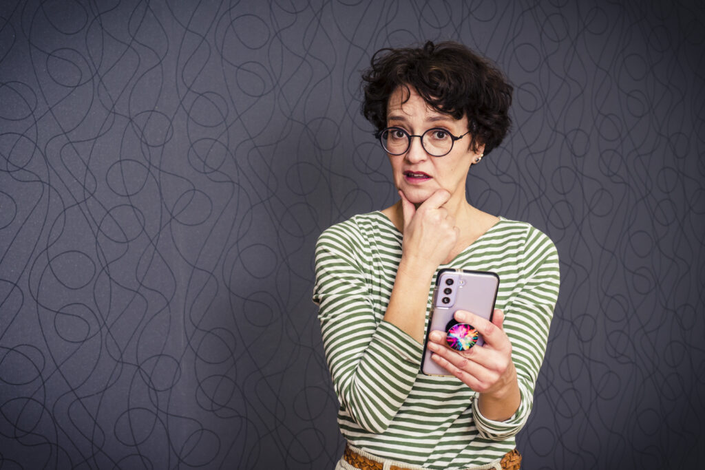 Frau hält das Handy in der Hand und blickt verwundert