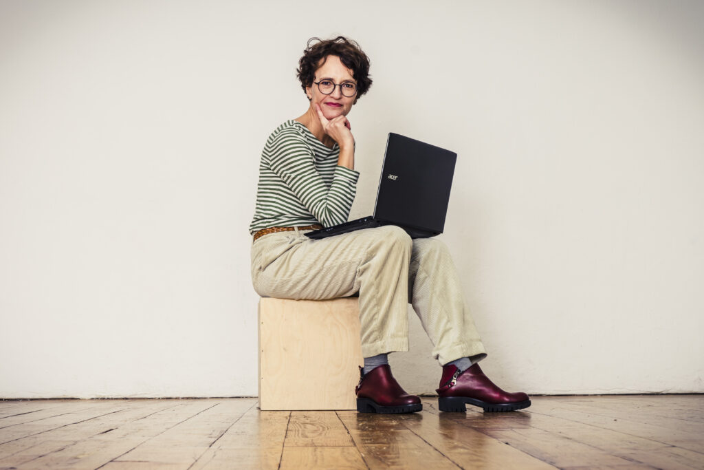 Eva Dragosits sitzt mit einem Laptop auf einem Hocker